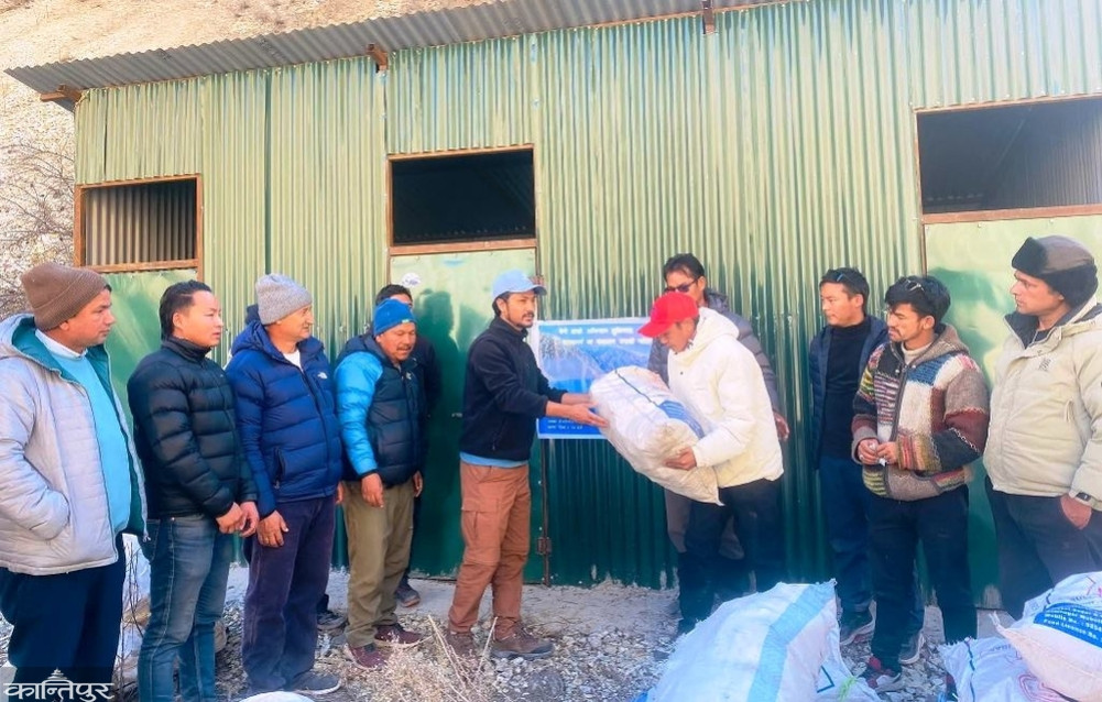 A young man alone picking up garbage piled up on the 'Phoksundo Trail'
